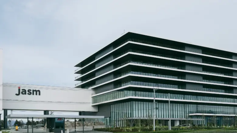 JASM熊本工場オフィス棟の外観。モダンなデザインの建物が広がり、ガラス張りのエントランスと整備された緑地が特徴的です。