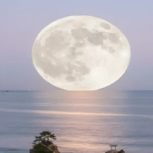 糸島・桜井二見ヶ浦の海上に昇るスーパームーン。夕焼け空に浮かぶ満月が海面に反射して幻想的に輝く。